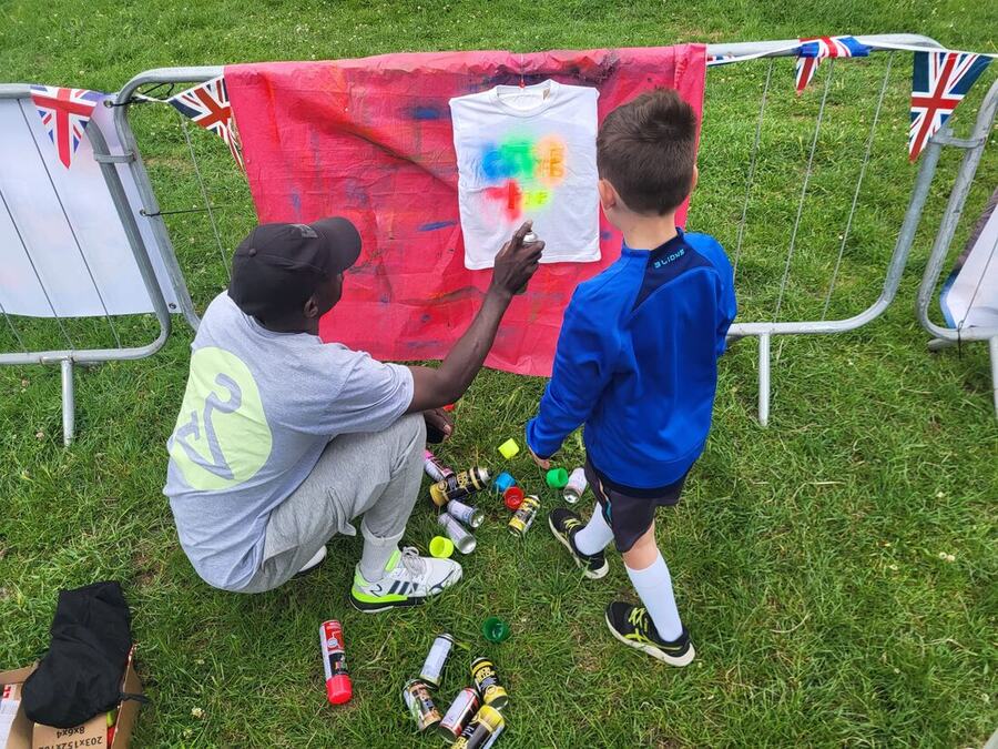 A child spraying a t-shirt against the printing backdrop