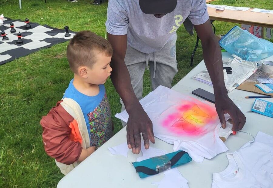A POSITIVI-TEES mentor guiding a younger child through designing a t-shirt