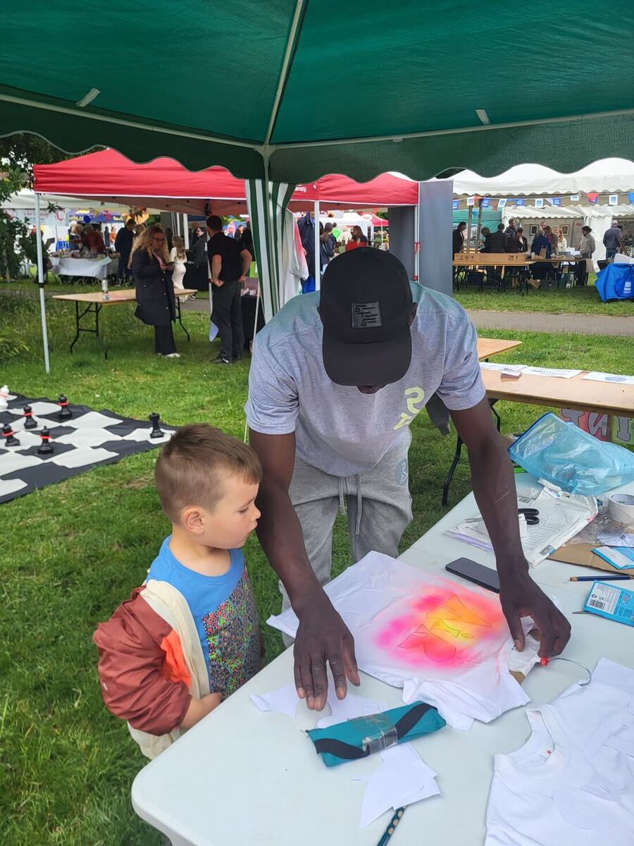 A POSITIVI-TEES mentor guiding a younger child through designing a t-shirt